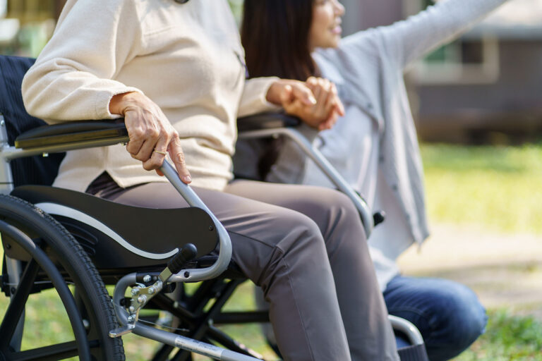 Young woman point out something in the distance to elderly woman sitting in wheel chair.